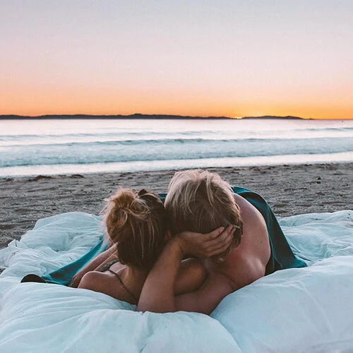 Psychic Solo performing a love rekindling ritual with two red candles being moved closer together, surrounded by dried hibiscus flowers and a photo of a couple.